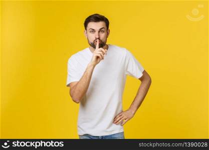 young man making silence gesture, shhhhh. Isolated over yellow background. young man making silence gesture, shhhhh. Isolated over yellow background.