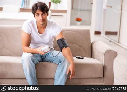 Young man measuring blood pressure at home