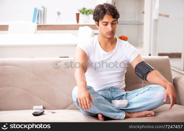 Young man measuring blood pressure at home