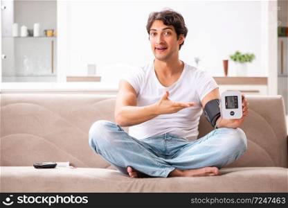 Young man measuring blood pressure at home