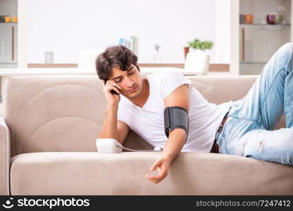 Young man measuring blood pressure at home. The young man measuring blood pressure at home