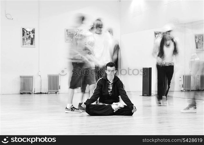 young man meditating in lotus position at dance studio