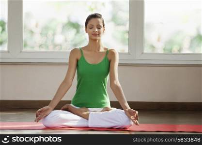 Young man meditating in morning on exercise mat
