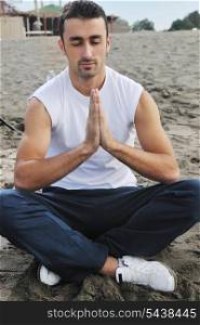 young man meditating yoga in lotus positin on the beach at early morning