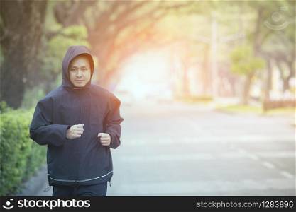 young man morning exercise by running on town street with beautiful light background