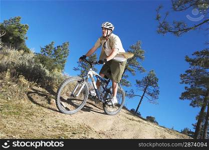 Young man mountain biking through field