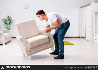 Young man moving furniture at home