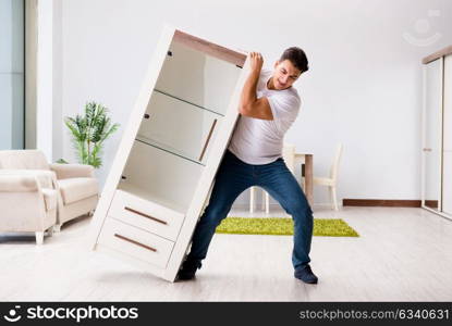 Young man moving furniture at home