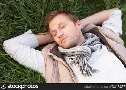 Young man napping alone on grass
