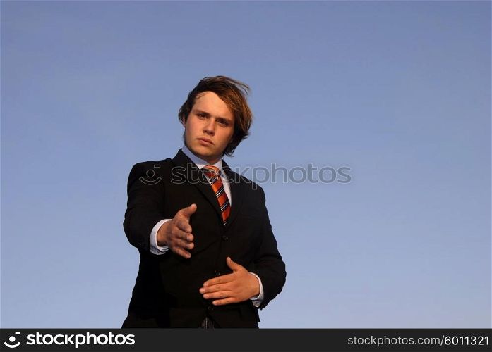 young man offering hand with the sky as background