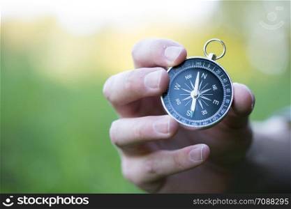 Young man on an adventure is holding a compass in his hand for finding is route