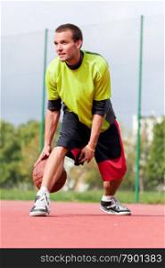 Young man on basketball court dribbling with ball. Streetball, training, activity. Real and authentic