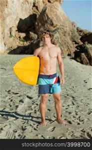 Young man on beach with surfboard