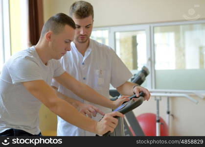 Young man on exercise bicycle in physiotherapy gym center