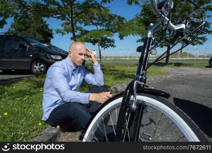 young man on roadside with broken bicycle