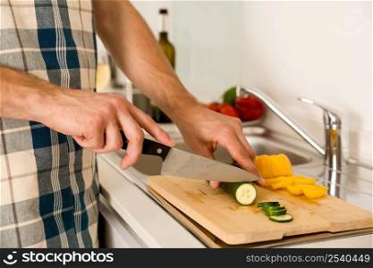 Young man on the kitchen cuting vegetables to cook