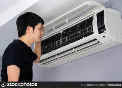young man open the air conditioner indoor at home