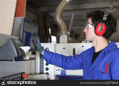 Young man operating factory machinery
