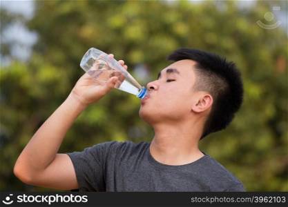 young man or teenager drinking water from plastic bottle