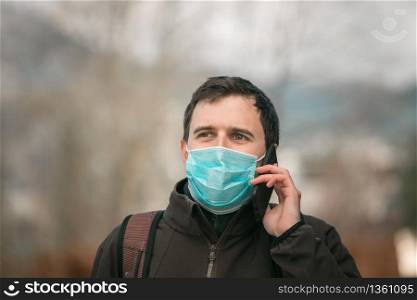 Young man outdoors wearing a face mask and smartphone. Corona and flu season.