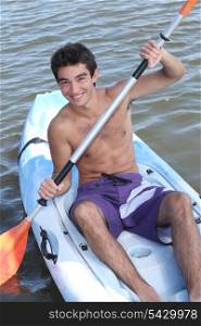Young man paddling in an open kayak
