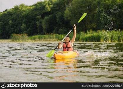 young man paddling kayak with lots splashes lake