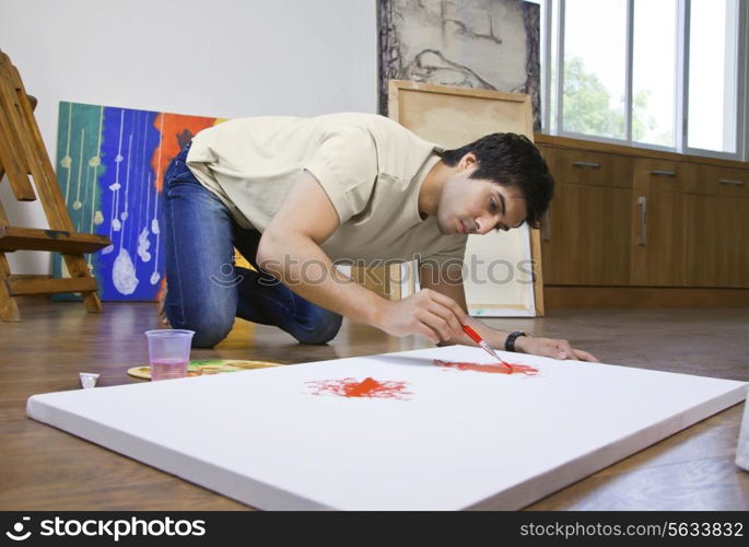 Young man painting on an artist&rsquo;s canvas at art studio