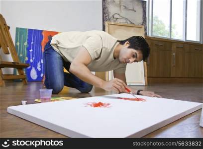 Young man painting on an artist&rsquo;s canvas at art studio