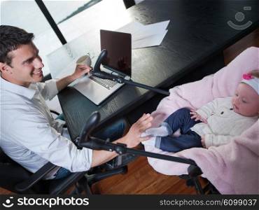 young man parent working on laptop computer at home office and take care of baby