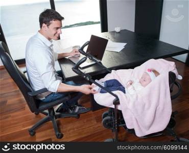 young man parent working on laptop computer at home office and take care of baby