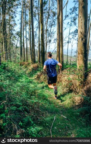 Young man participating in a trail race through the forest. Young man doing trail