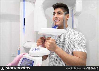 Young man patient standing in x-ray machine. Panoramic radiography. High quality photo.. Young man patient standing in x-ray machine. Panoramic radiography.