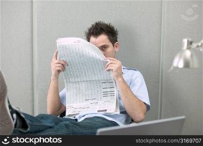 Young Man Peeking From Behind Newspaper