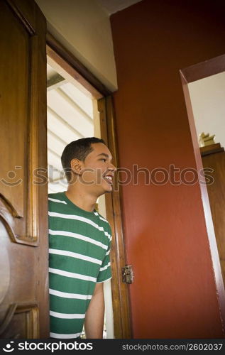 Young man peeking through a door