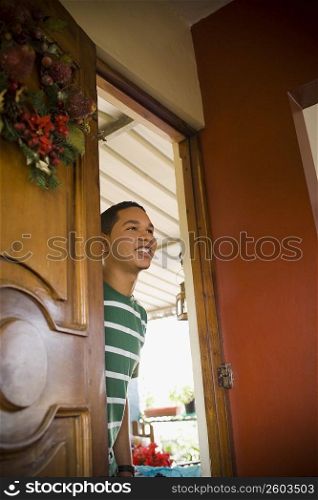 Young man peeking through a door