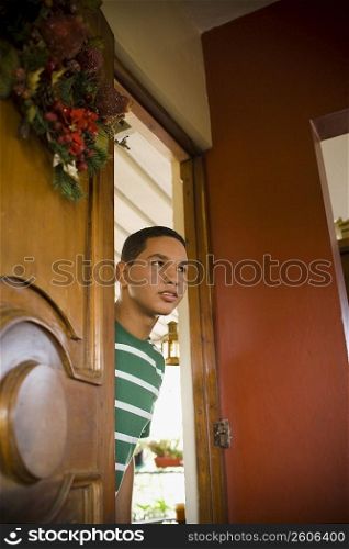 Young man peeking through a door