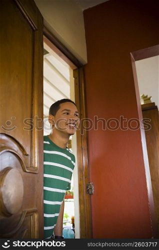 Young man peeking through a door and smiling