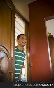 Young man peeking through a door and smiling