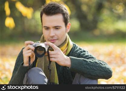 Young man photographing in park during autumn