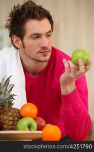 Young man picking an apple from a fruit bowl