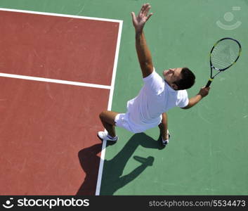 young man play tennis outdoor on orange tennis court at early morning