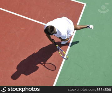 young man play tennis outdoor on orange tennis court at early morning