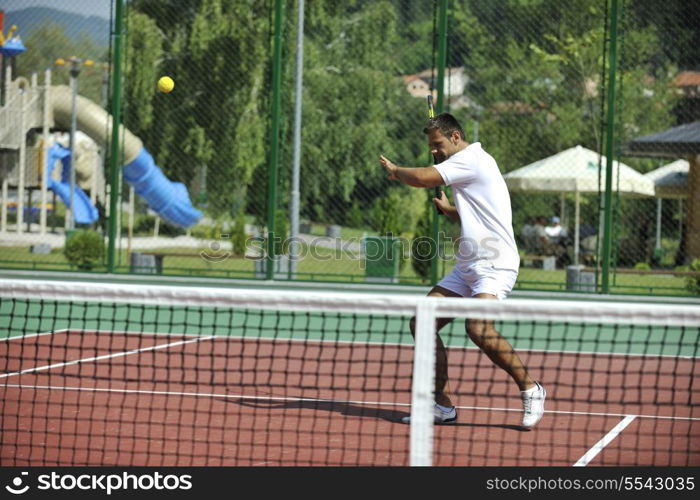 young man play tennis outdoor on orange tennis court at early morning