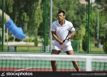 young man play tennis outdoor on orange tennis court at early morning