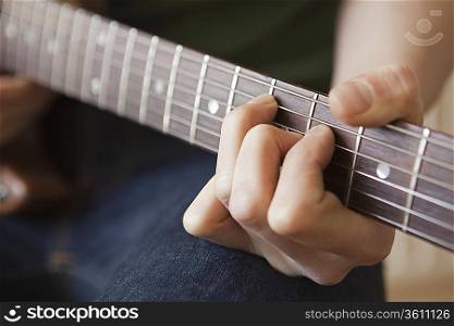 Young man playes chord on guitar