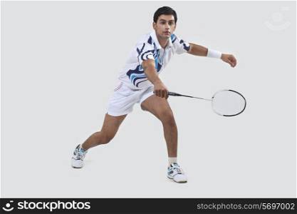 Young man playing badminton isolated over gray background