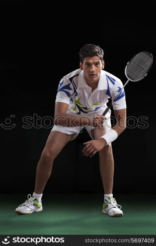 Young man playing badminton over black background