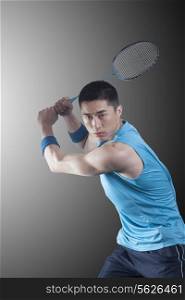 Young man playing badminton, racket raised