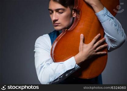 Young man playing cello in dark room