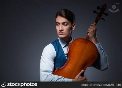 Young man playing cello in dark room